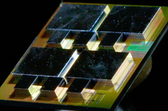  Detail view of the system-on-interposer, with a companion electro-optical router for each computing die and two additional routers for primary IO. Light coupling to the optical network on interposer is achieved on fiber coupling visible on the bottom-right corner. Photo Credit: KAM productions.