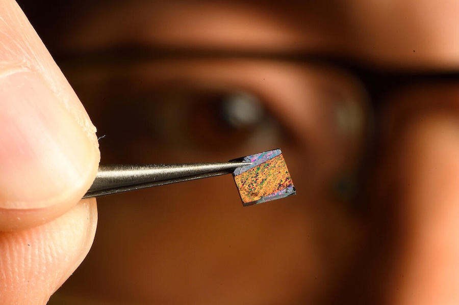 Peng Zheng from JHU shows off the heart of the blood test, a chip with a groundbreaking nanostructured surface on which blood is tested. Credit: Will Kirk/Johns Hopkins University.