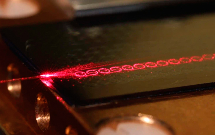 The amplifier developed by Chalmers researchers is compact, measuring just a few centimeters across, yet it can process ten times larger amounts of data per second than current optical communication systems. This innovation leverages a unique combination of design and material selection, providing technical benefits such as minimal noise and a compact form factor. The amplifier features a pattern of spiral-shaped, interconnected waveguides that efficiently direct the laser beam with high precision and minimal loss. Image credit: Chalmers University of Technology | Vijay Shekhawat.