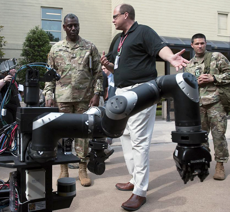 Dr. Stuart Young [center] presents an autonomous robot to Maj. Gen. Cedric Wins.