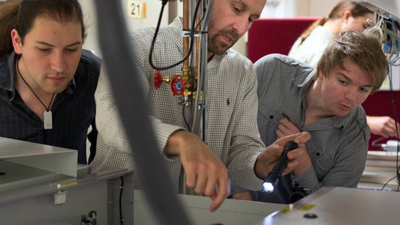 Faccio, center, working on laser system alignment and optimization with students.
