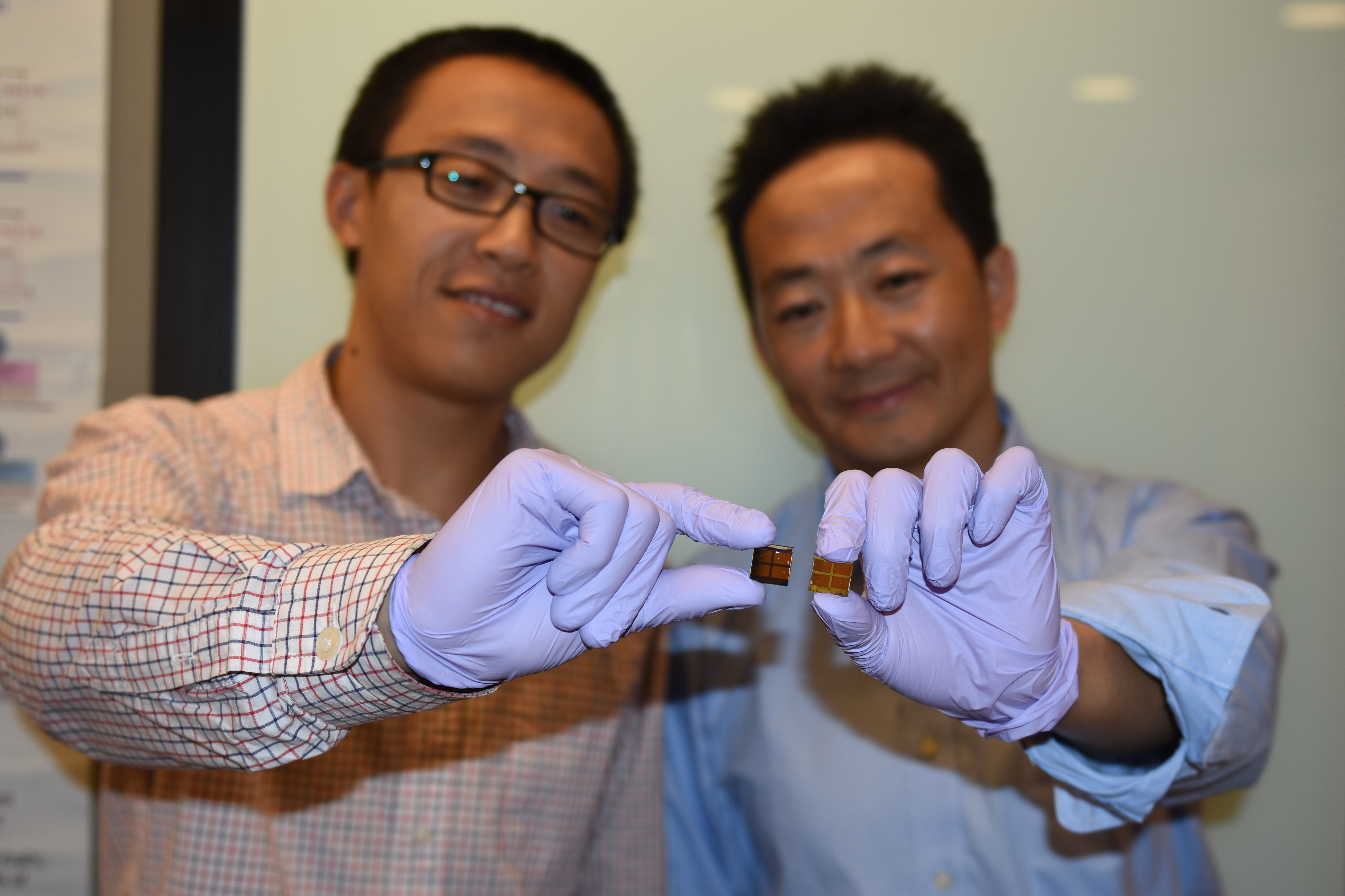 Dr Jiang (L) with MAPbI3 solar cell; Dr Wang (R) holds an iodine-degraded cell.
