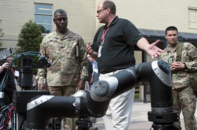 Dr. Stuart Young [center] presents an autonomous robot to Maj. Gen. Cedric Wins.