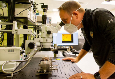 Steve Adamshick inspects an AIM/Spark Photonics EWD PIC chip.