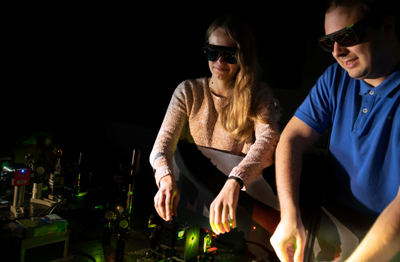 Fiona Cole and Jonas Zähringer adjusting a fluorescence microscope.